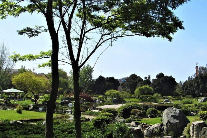 A park with trees, rocks, and a gazebo. 2