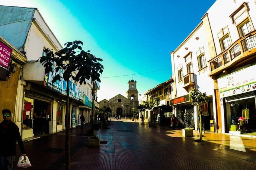 A street with shops, a clock tower, and a clear blue sky. 5