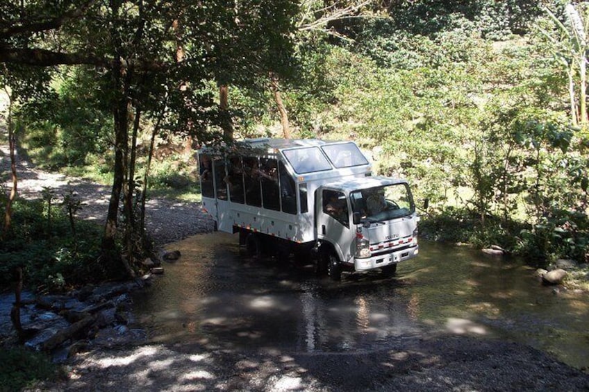 A white truck with a camper on a forested road. 4