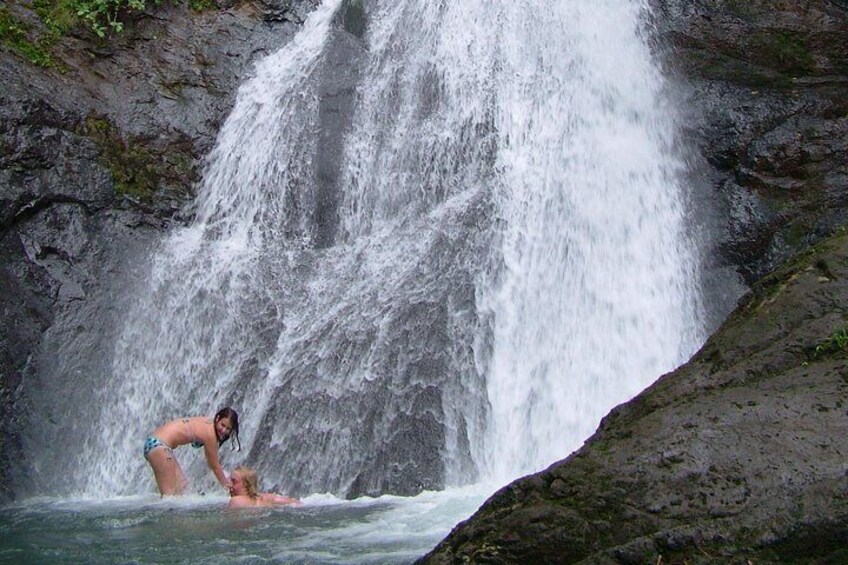 A waterfall with a person swimming in the water. 5