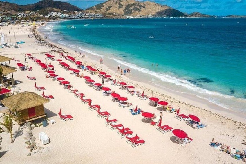 A beach with rows of red umbrellas and lounge chairs. 3