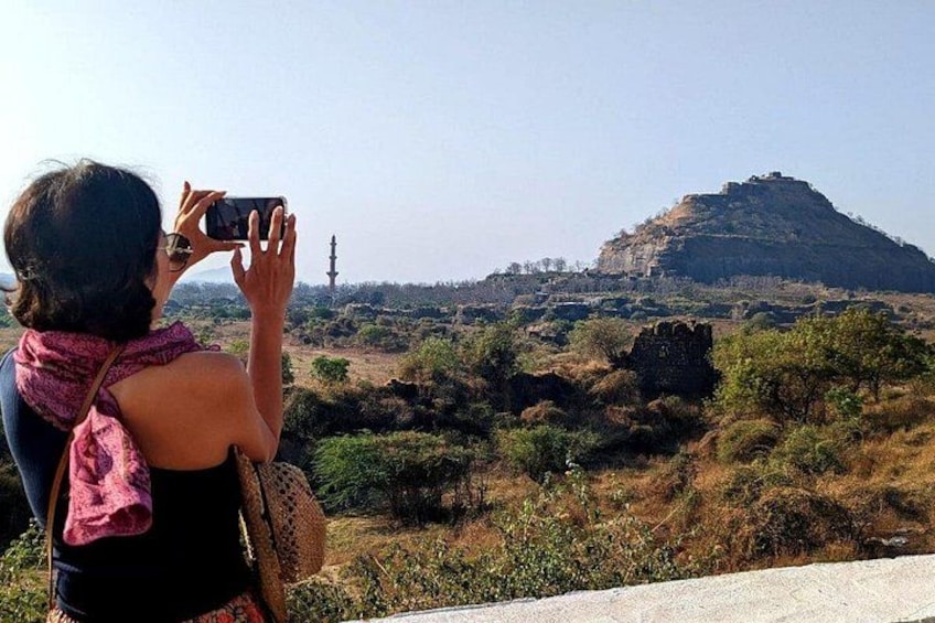 Una persona fotografiando una estructura en la cima de una colina con una torre. 3