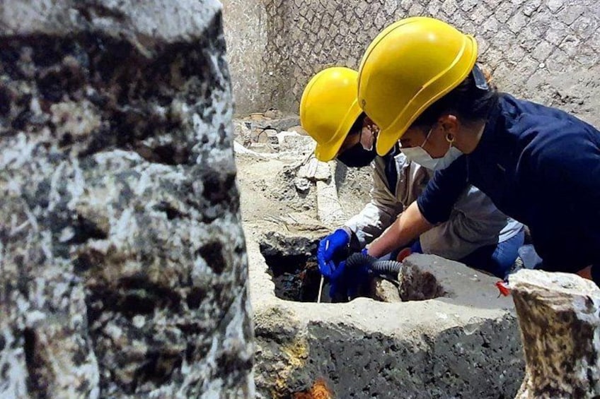 Zwei Arbeiter mit Schutzhelmen und Handschuhen arbeiten auf einer Baustelle. 4