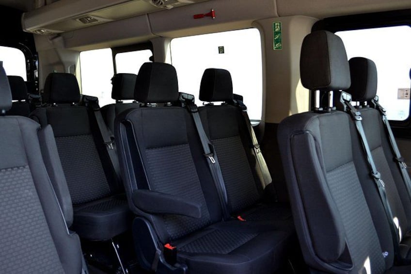 Interior de vehículo con cuatro filas de asientos, cinturones de seguridad y reposacabezas. 2