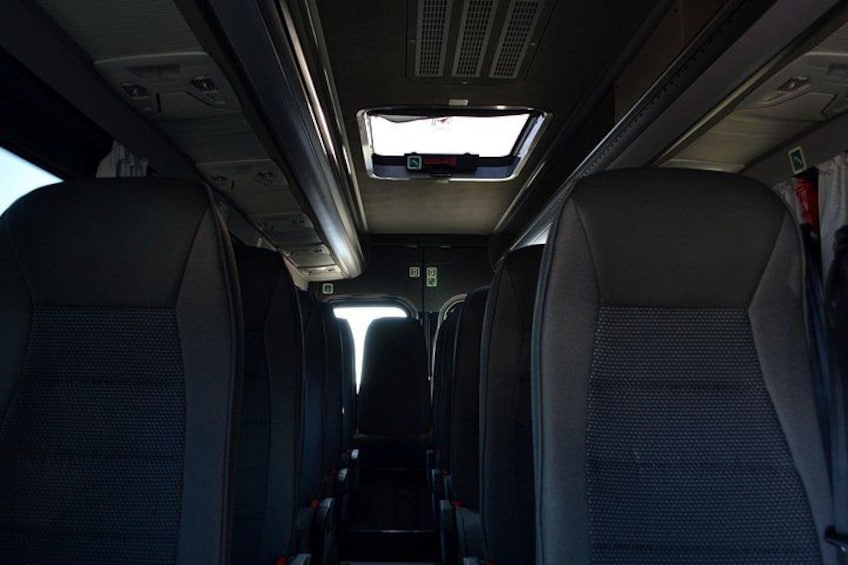 El interior de un tren con hileras de asientos y compartimentos superiores. 5