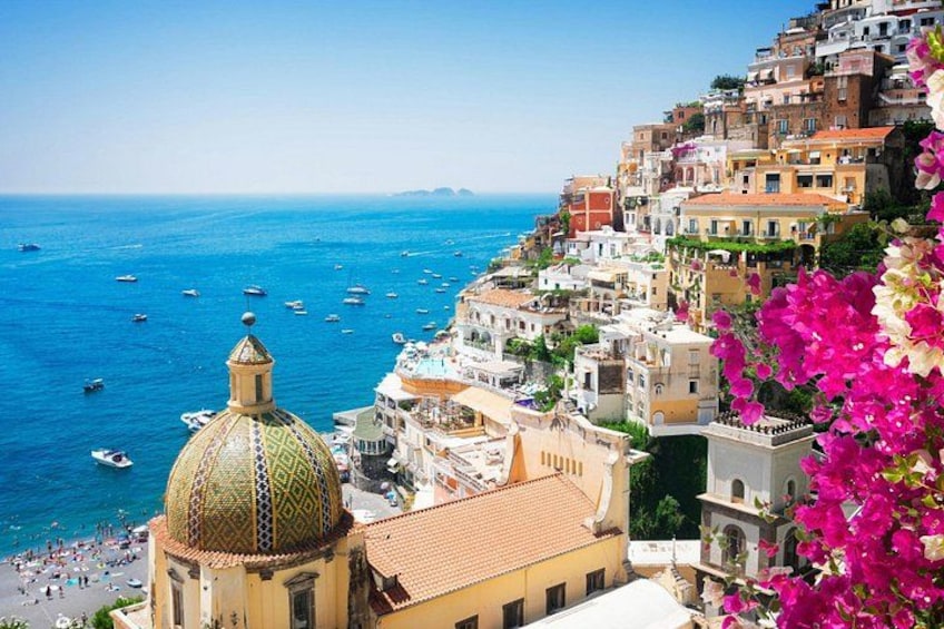 Una cittadina costiera con edifici colorati, una cupola imponente e barche sul mare. 2