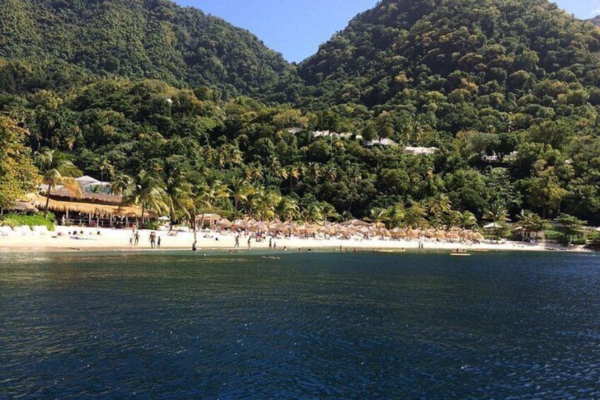 A beach with people, palm trees, and a mountain in the background. 3