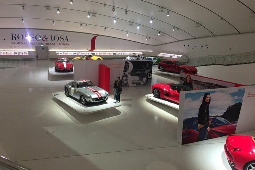A car showroom with multiple car displays and a prominent red sports car. 3