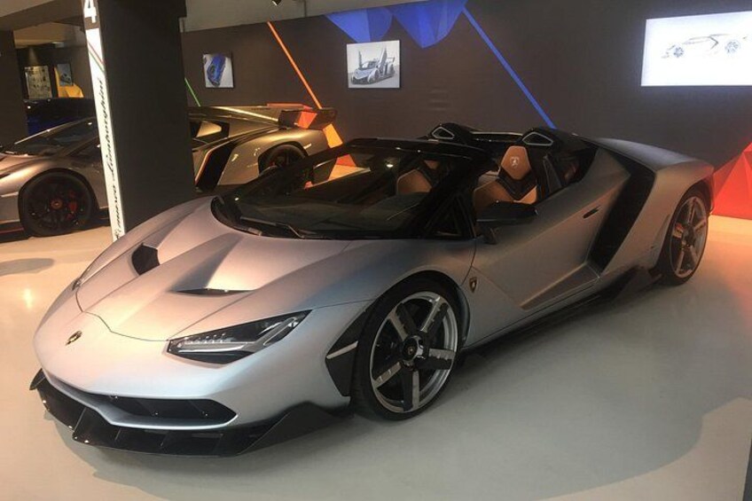 A silver sports car with a convertible top, black interior, and large alloy wheels. 4