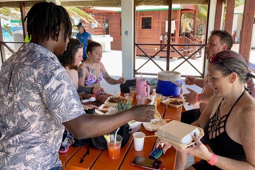 A group of people dining at an outdoor restaurant with wooden tables and chairs. 4