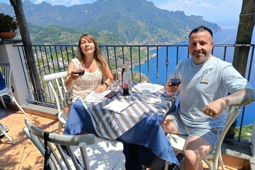 Two people seated at a table with a scenic mountain backdrop. 2