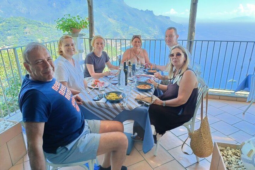 A group of people dining at a table with a scenic ocean view. 4