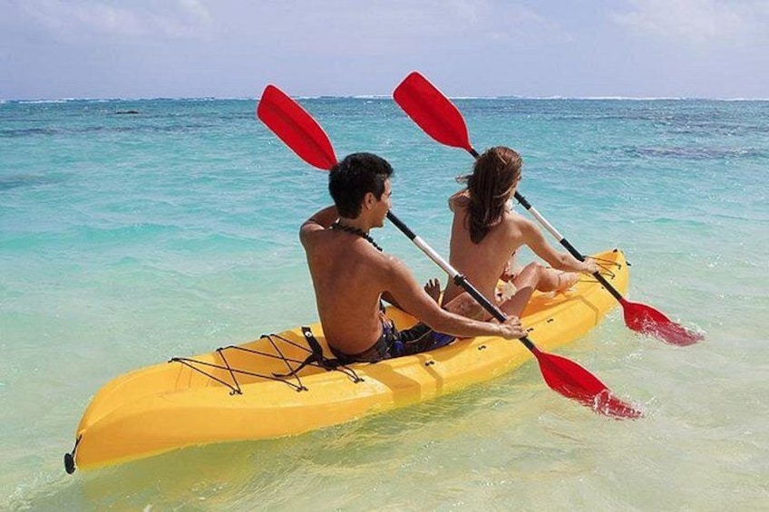 Twee personen kajakken op turquoise water. 1