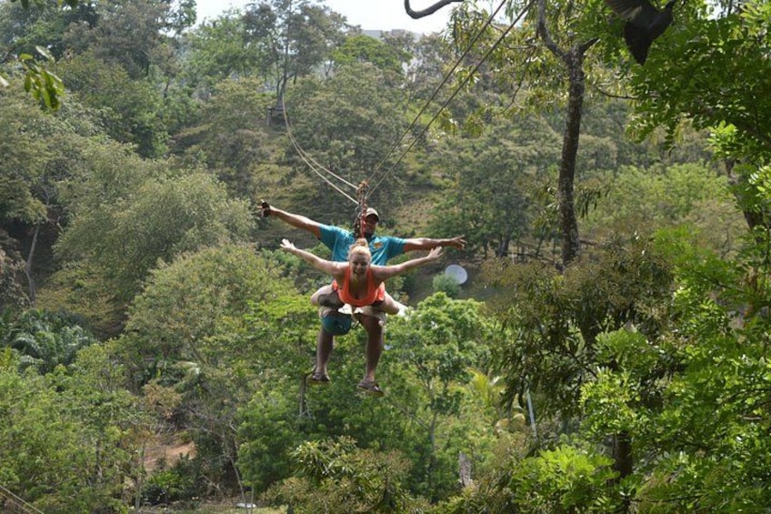 Two people swinging on a rope in a forested area. 4