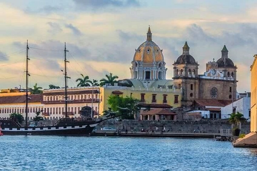 A waterfront with a prominent church with two domes, a large building with a clock tower, and a bridge. 5