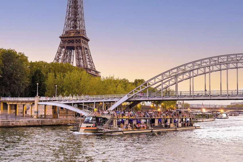 Eine Bootsfahrt mit Passagieren, eine Brücke und der Eiffelturm im Hintergrund. 5