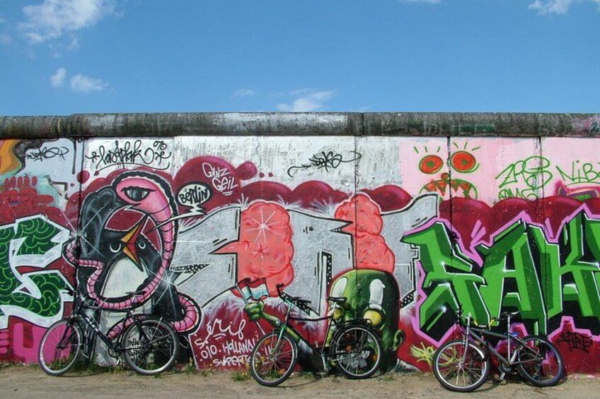 Eine Wand mit farbenfrohen Graffiti, darunter ein pinker Flamingo und ein grünes Fahrrad. 2