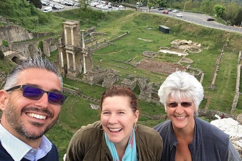 A group of people standing on a hill overlooking ancient ruins with columns and stone structures. 1