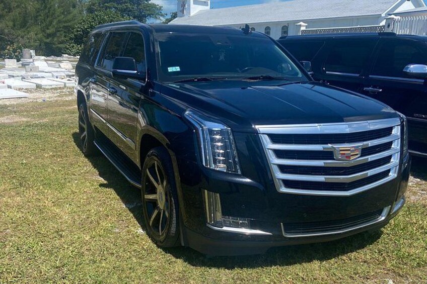 En svart Cadillac-SUV parkerad på en gräsmatta, med en byggnad i bakgrunden. 3