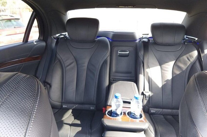 Interior de coche con asientos de cuero negro, consola central con botellas de agua y techo solar. 4