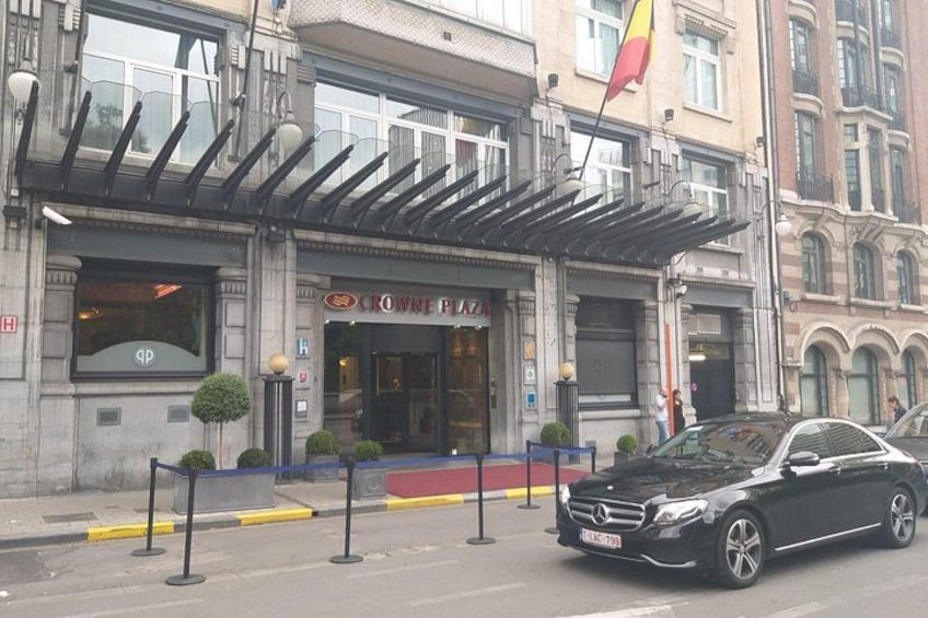 Un automóvil negro estacionado frente a un edificio con un letrero que dice 'Crown Plaza'. 3