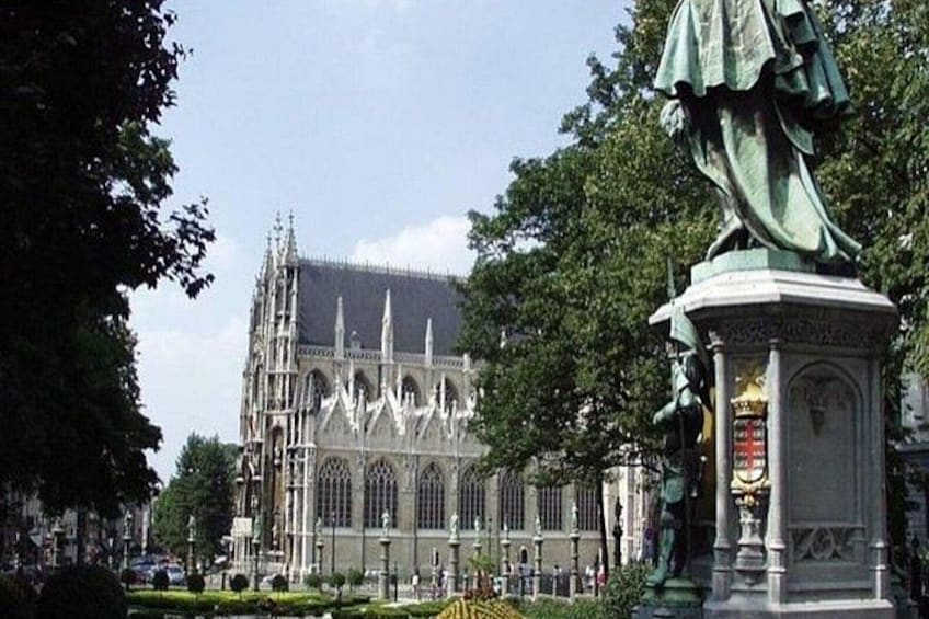 En gotisk katedral med utsmyckade tornspiror och en staty i förgrunden. 4