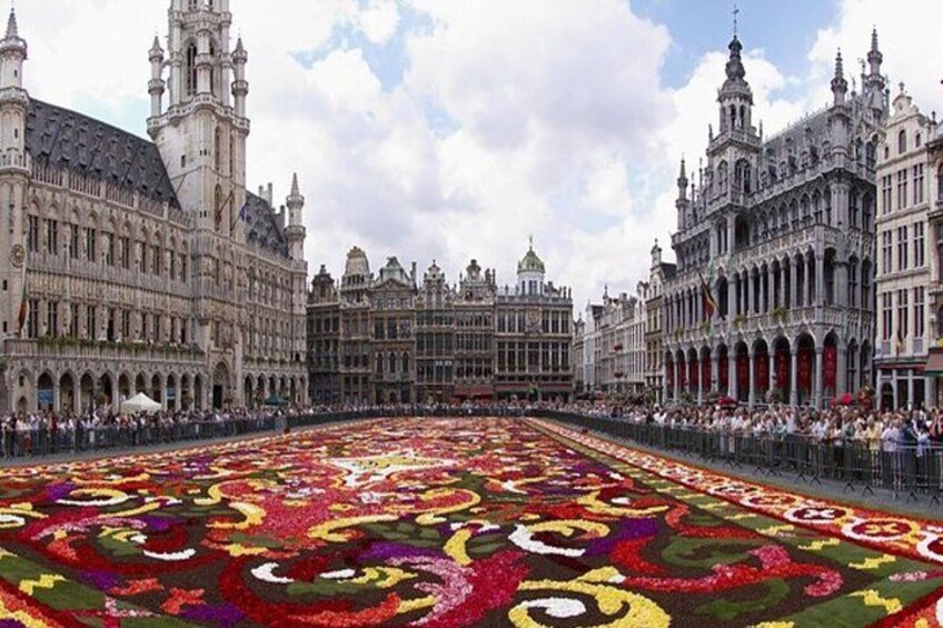 A large, ornate building with intricate architecture and a vast floral carpet in front. 4
