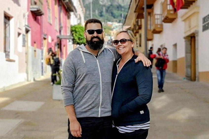 A couple standing on a street with buildings on either side. 1