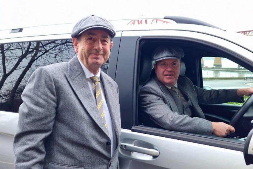 Two men in suits and hats standing next to a car. 5