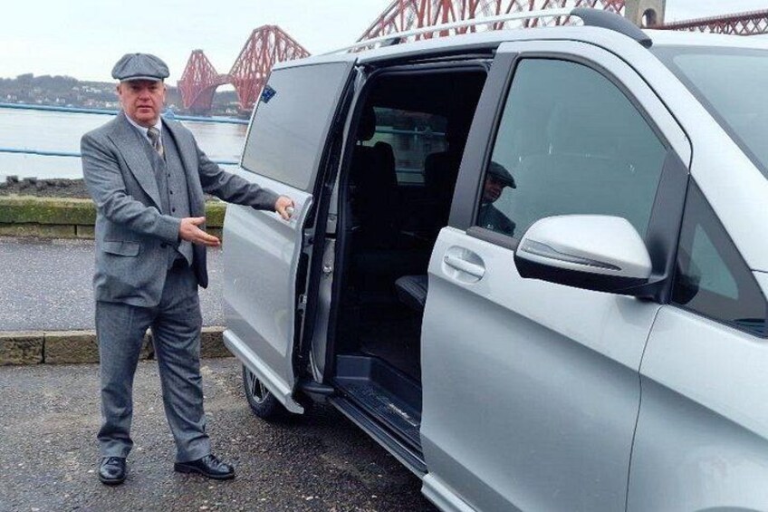 A man in a suit opening a van door. 2