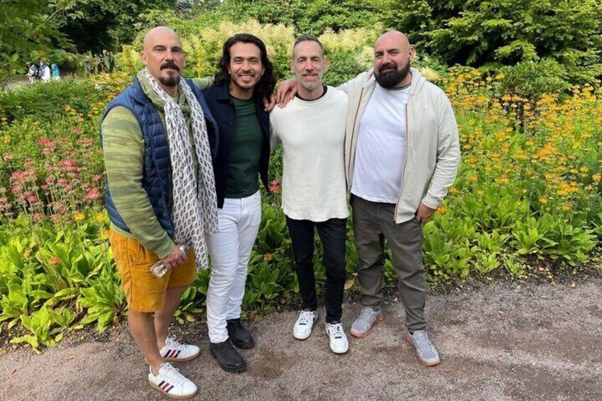 Four people standing in a garden with greenery and flowers. 3