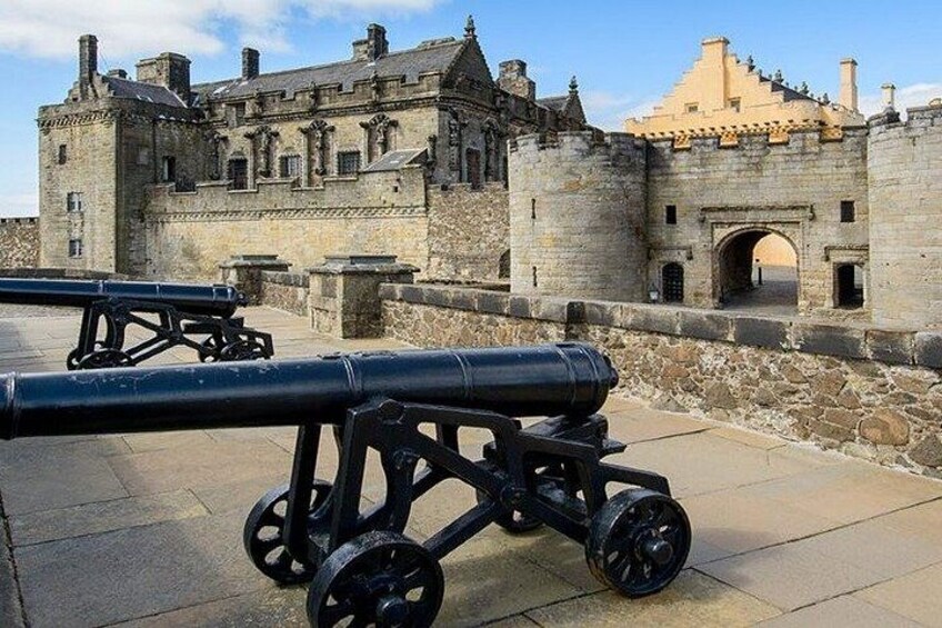 A historic stone castle with cannons in front. 5
