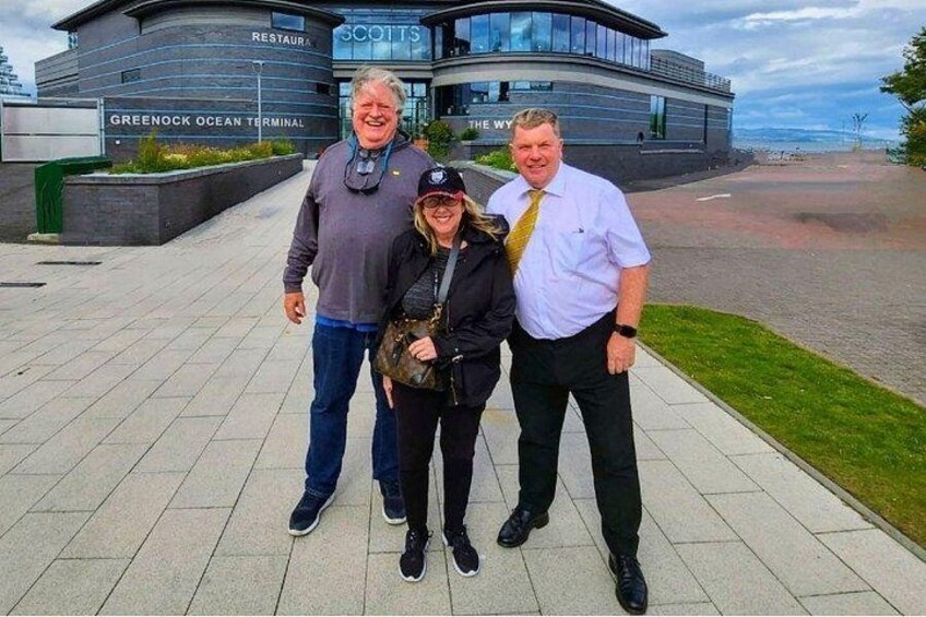 Three people standing in front of a building with a sign that reads 'GREENOCK OCEAN TERMINAL' and 'THE WY.' 2