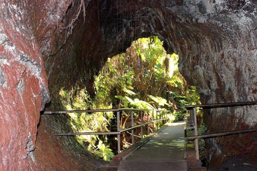 A stone tunnel with a metal walkway and railings, surrounded by greenery. 2