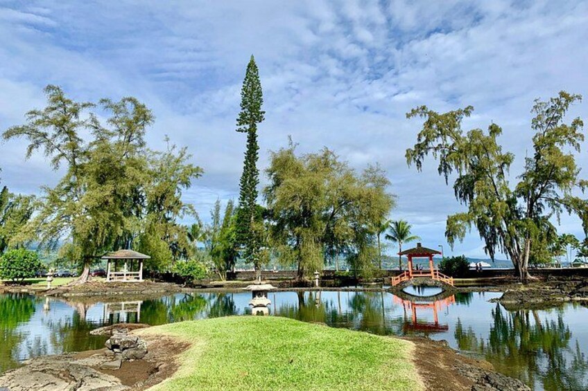 A tranquil park with a pond, two gazebos, and lush trees. 2