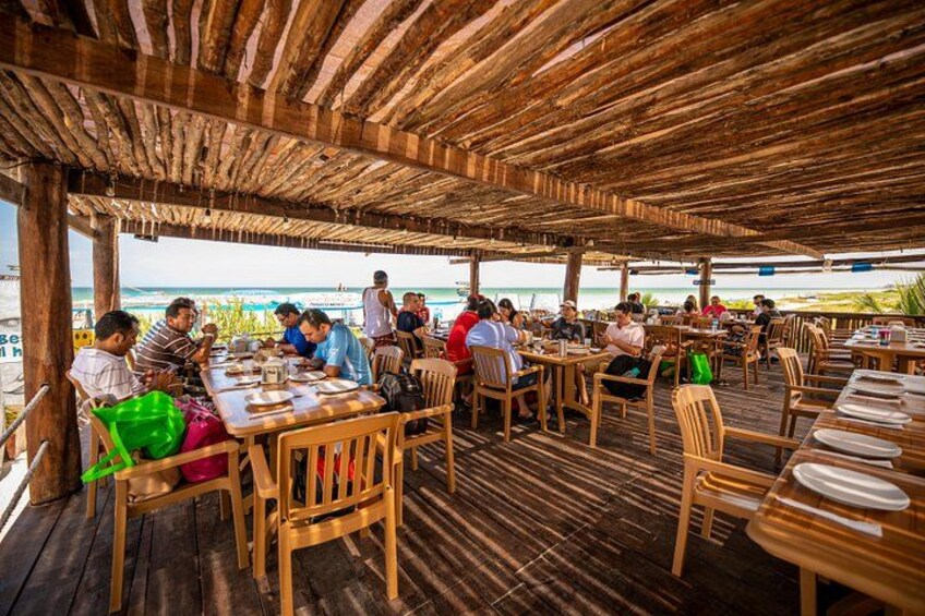 A wooden deck with tables and chairs, overlooking a beach. 3