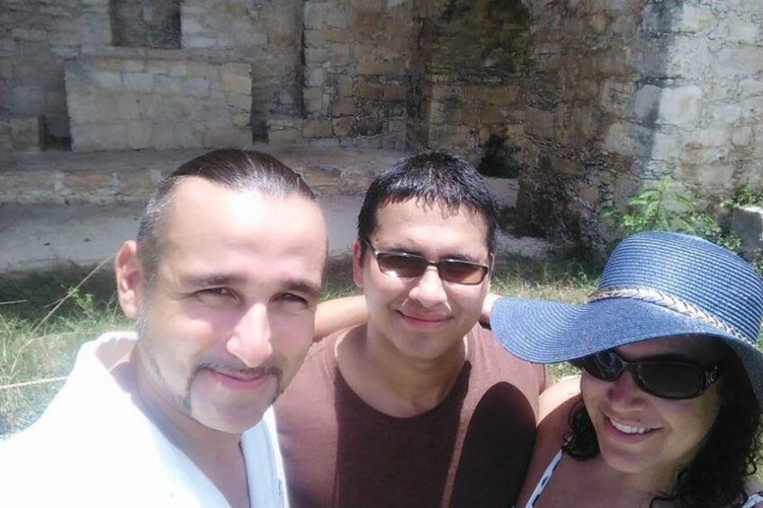Trois personnes posent devant un mur de pierre. 3