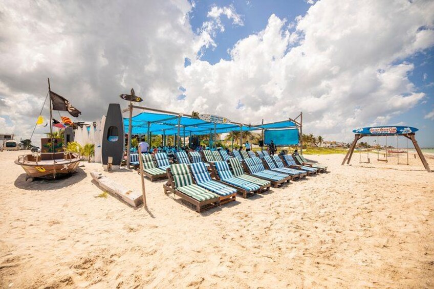 A beach with lounge chairs, a boat, and a shaded area. 3