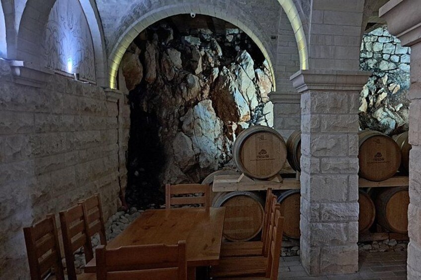 Un sótano con paredes de piedra, barriles de madera y una mesa con sillas. 2