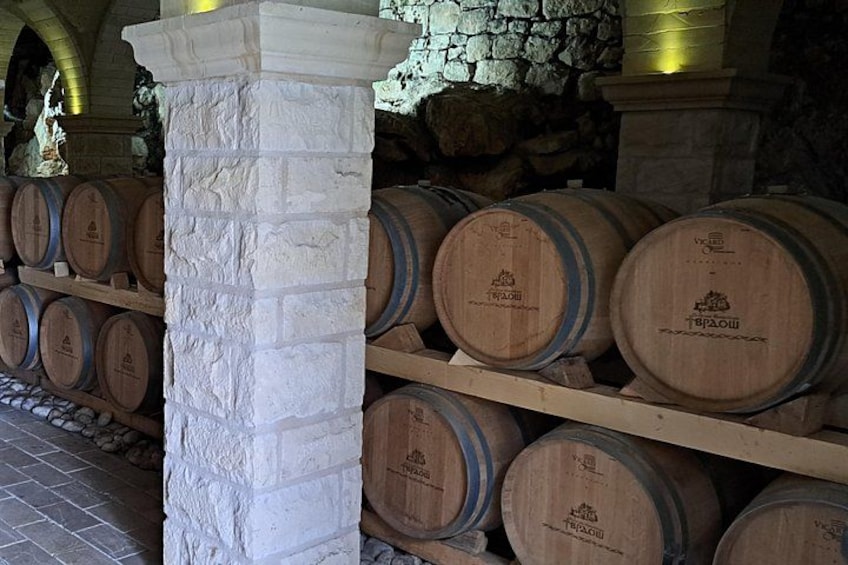 Barricas de madera apiladas en estantes, una pared de piedra y una columna de piedra. 4