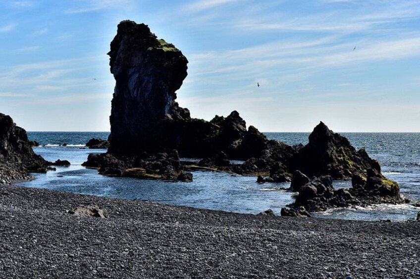 A rocky coastline with prominent rock formations and a pebbly beach. 4