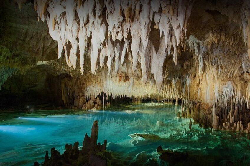 A cave with stalactites, a pool of water, and rock formations. 2