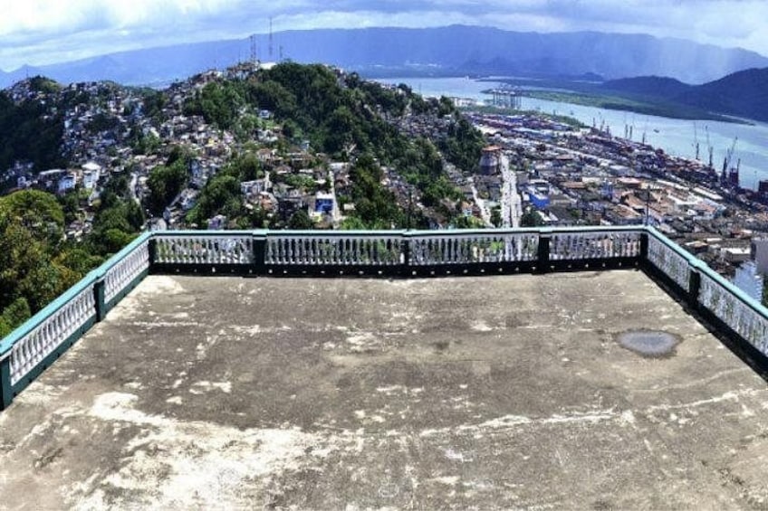 Eine Beton-Aussichtsplattform mit Metallgeländer, die auf eine dicht besiedelte Stadt mit einem Fluss und Hügeln im Hintergrund blickt. 4