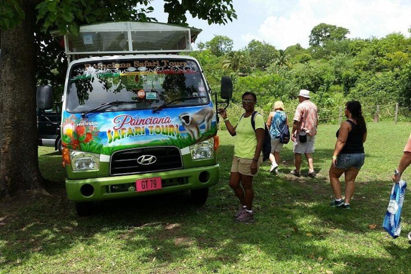 A green safari tour bus with passengers and a group of people standing nearby. 3