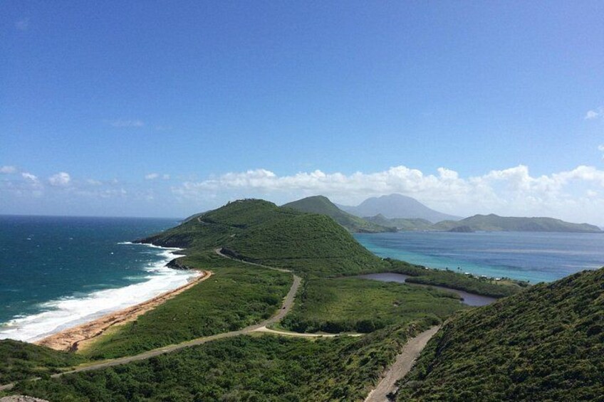 A coastal landscape with a beach, a winding road, and a mountain. 3