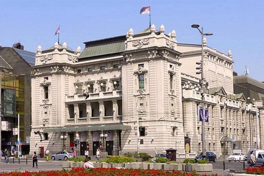 Un bâtiment historique à l’architecture riche et ornée, un drapeau et un parterre de fleurs bien entretenu. 5