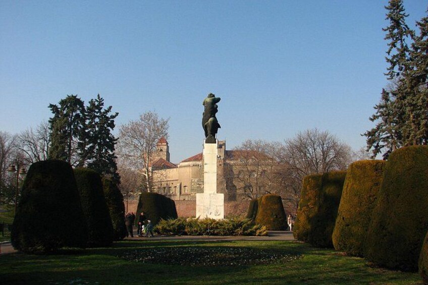 Une statue dans un parc, avec un bâtiment en arrière-plan. 4