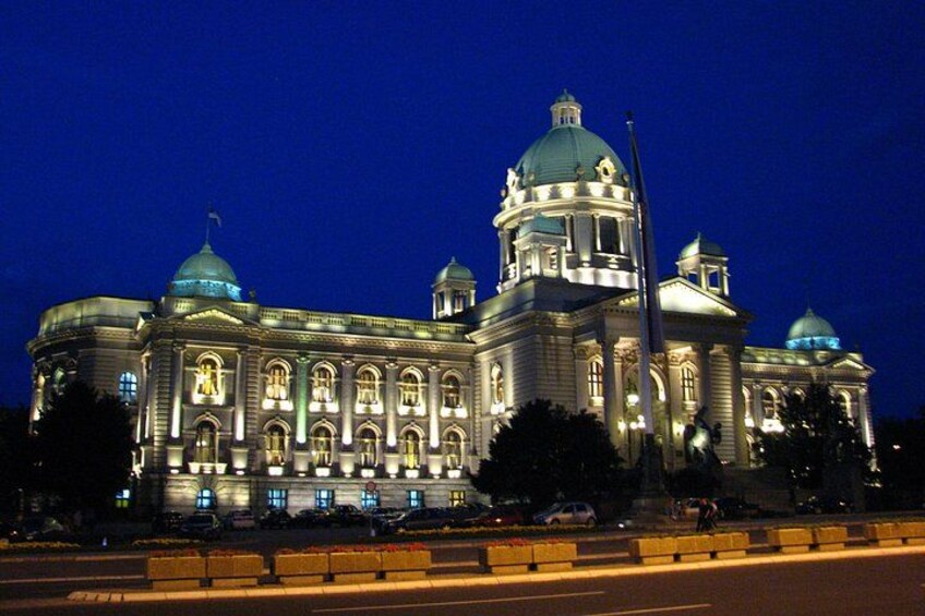 Un grand bâtiment illuminé, doté de toits en forme de dôme et de fenêtres en arc de cercle, visible la nuit. 2