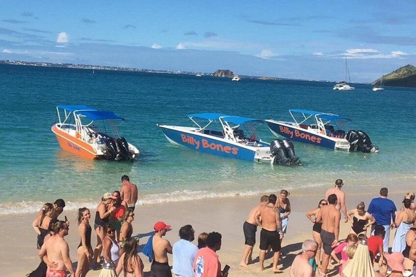 A beach with people and three boats named 'Billy Bones' anchored in the water. 1