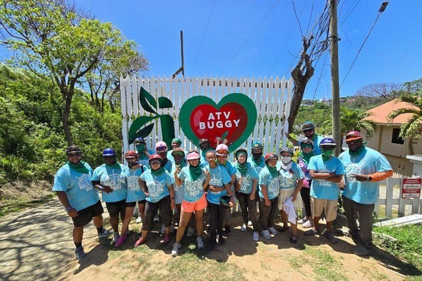 A group of people in matching shirts standing in front of a sign with a heart and the text 'ATV BUGGY'. 2